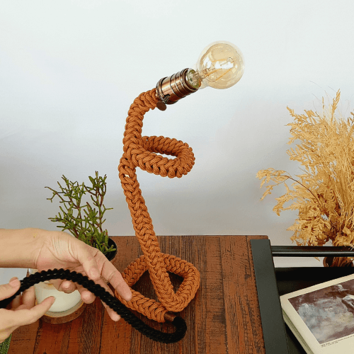 luminaria de mesa em macrame leve e macia na cor terracota sobre mesa de madeira
